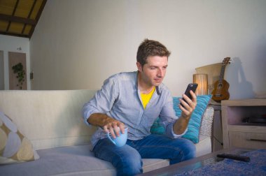 oturma odası kanepe oturan genç güzel çekici ve mutlu adam kanepede internet mobil dating veya hatta flört telefonu kullanarak ağ rahat zevk internet sosyal medya uygulaması