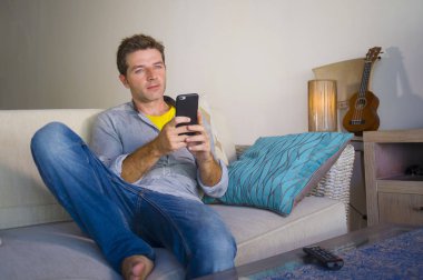 oturma odası kanepe oturan genç güzel çekici ve mutlu adam kanepede internet mobil dating veya hatta flört telefonu kullanarak ağ rahat zevk internet sosyal medya uygulaması