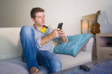 oturma odası kanepe oturan genç güzel çekici ve mutlu adam kanepede internet mobil dating veya hatta flört telefonu kullanarak ağ rahat zevk internet sosyal medya uygulaması