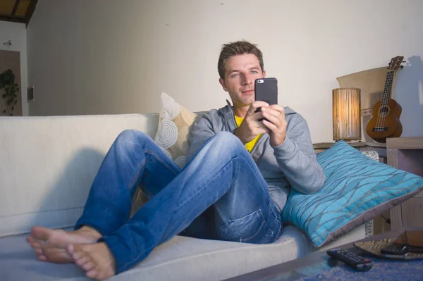 oturma odası kanepe oturan genç güzel çekici ve mutlu adam kanepede internet mobil dating veya hatta flört telefonu kullanarak ağ rahat zevk internet sosyal medya uygulaması
