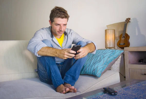 oturma odası kanepe oturan genç güzel çekici ve mutlu adam kanepede internet mobil dating veya hatta flört telefonu kullanarak ağ rahat zevk internet sosyal medya uygulaması