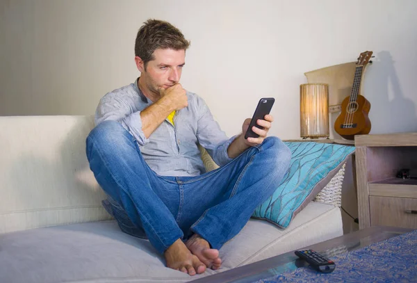 oturma odası kanepe oturan genç güzel çekici ve mutlu adam kanepede internet mobil dating veya hatta flört telefonu kullanarak ağ rahat zevk internet sosyal medya uygulaması