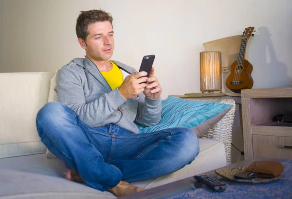 oturma odası kanepe oturan genç güzel çekici ve mutlu adam kanepede internet mobil dating veya hatta flört telefonu kullanarak ağ rahat zevk internet sosyal medya uygulaması
