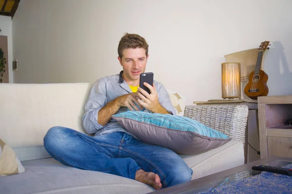 oturma odası kanepe oturan genç güzel çekici ve mutlu adam kanepede internet mobil dating veya hatta flört telefonu kullanarak ağ rahat zevk internet sosyal medya uygulaması