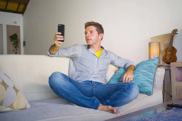 oturma odası kanepe oturan genç güzel çekici ve mutlu adam kanepede internet mobil dating veya hatta flört telefonu kullanarak ağ rahat zevk internet sosyal medya uygulaması