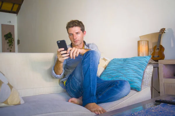 oturma odası kanepe oturan genç güzel çekici ve mutlu adam kanepede internet mobil dating veya hatta flört telefonu kullanarak ağ rahat zevk internet sosyal medya uygulaması