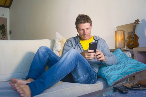 oturma odası kanepe oturan genç güzel çekici ve mutlu adam kanepede internet mobil dating veya hatta flört telefonu kullanarak ağ rahat zevk internet sosyal medya uygulaması