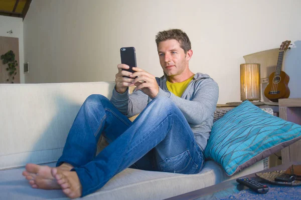 oturma odası kanepe oturan genç güzel çekici ve mutlu adam kanepede internet mobil dating veya hatta flört telefonu kullanarak ağ rahat zevk internet sosyal medya uygulaması