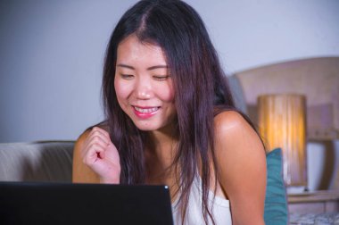 dizüstü bilgisayar ağ online teknoloji iletişim yaşam tarzı kavramı içinde neşeli üzerindeki Internet kullanan genç güzel Asyalı Çinli öğrenci kız mutlu ve evde rahat kanepe 