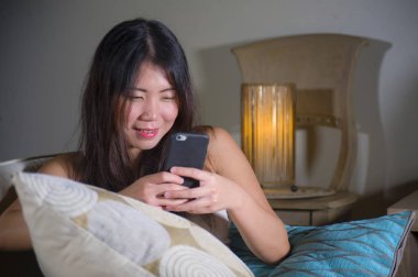 cep telefonu gülümseyen üzerinde Internet Sosyal medya app eğlence evde kanepe koltuk online iletişim yaşam tarzı kavramı içinde neşeli kullanan genç tatlı mutlu ve pretty Asya Kore kadın