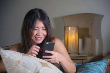 cep telefonu gülümseyen üzerinde Internet Sosyal medya app eğlence evde kanepe koltuk online iletişim yaşam tarzı kavramı içinde neşeli kullanan genç tatlı mutlu ve pretty Asya Kore kadın