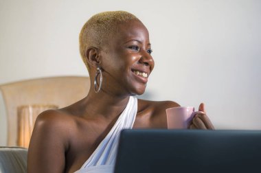 evde dizüstü bilgisayar üzerinde çalışan gülümseyen genç güzel mutlu siyah afro Amerikalı kadın girişimci bağımsız çalışma ve Internet serbest iş kanepe kanepede rahat