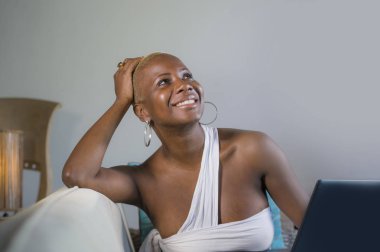 evde dizüstü bilgisayar üzerinde çalışan gülümseyen genç güzel mutlu siyah afro Amerikalı kadın girişimci bağımsız çalışma ve Internet serbest iş kanepe kanepede rahat