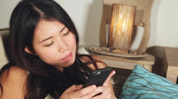 cep telefonu gülümseyen üzerinde Internet Sosyal medya app eğlence evde kanepe koltuk online iletişim yaşam tarzı kavramı içinde neşeli kullanarak genç tatlı mutlu ve güzel Asyalı Çinli kadın