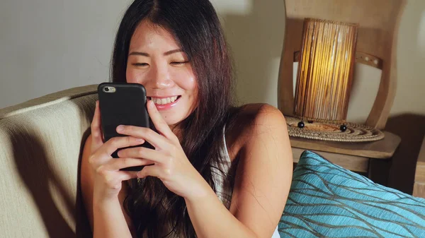 cep telefonu gülümseyen üzerinde Internet Sosyal medya app eğlence evde kanepe koltuk online iletişim yaşam tarzı kavramı içinde neşeli kullanan genç tatlı mutlu ve pretty Asya Kore kadın