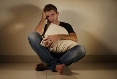 tek başına evde oturan üzgün holding yastık üzüntü kavramı depresyon sorunu acı seyir stüdyo gölgeli ve dramatik ışık yerde ağlıyor genç umutsuz ve depresif adam