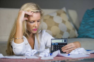 attractive worried and desperate blond woman calculating domestic money expenses doing paperwork and bank bills accounting with calculator suffering stress in financial problem and depression clipart