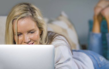 güzel ve sarışın bir kadın 40'lı modern yaşam tarzı concep dairede, kanepe kanepede rahat yalan laptop çalışma Internet kullanarak evde rahat mutlu portre kadar kapatın