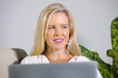 güzel portresi ve mutlu zarif sarışın kadın erken 40s evde rahat oturma odası yaşam tarzı kavramında rahat çalışma dizüstü bilgisayarda internet kullanımı kapat