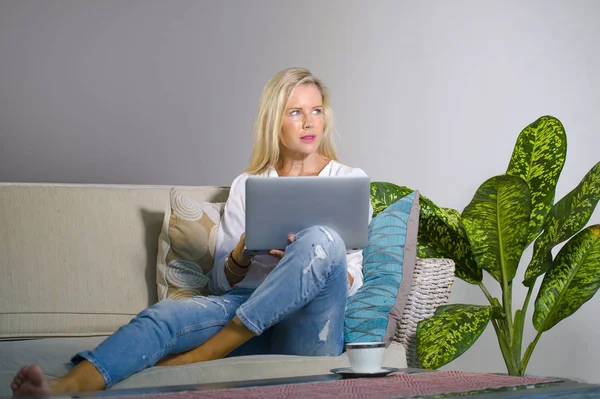 güzel ve mutlu zarif sarışın kadın erken 40s evde oturma odası dizüstü bilgisayar çalışma rahat kanepe kanepede yaşam tarzı kavram modern daire, internet kullanımı rahat