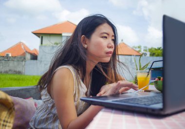 genç çekici ve mutlu Asian açık havada çalışan dijital göçebe başarı iş online sosyal medya backpacker seyahat blogcu olarak tropikal kafede dizüstü bilgisayar ile rahat Korece