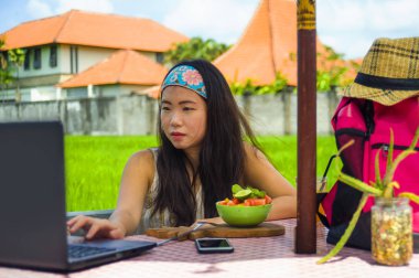 genç çekici ve mutlu Asian açık havada çalışan dijital göçebe başarı iş online sosyal medya backpacker seyahat blogcu olarak tropikal kafede dizüstü bilgisayar ile rahat Korece