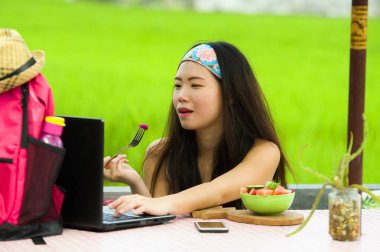 Açık havada çalışan genç çekici ve mutlu Asya Kore Dijital göçebe gibi online sosyal medya blogger seyahat başarı iş sağlıklı salata yemek dizüstü bilgisayar ile rahat