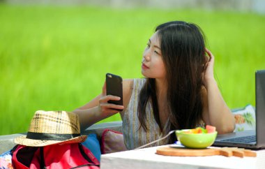 Genç güzel ve mutlu Asya çalışan dijital göçebe kadın açık havada kahve dükkanı masada dizüstü bilgisayar ve cep telefonu Internet online iş ile rahat Korece blogger seyahat 