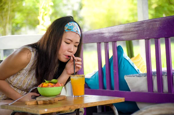 Genç güzel ve mutlu sağlıklı salata organik gıda açık havada brunch keyfi Cafe'de yemek portakal suyu içme Asyalı Çinli kadın yaz tatillerini rahat seyahat