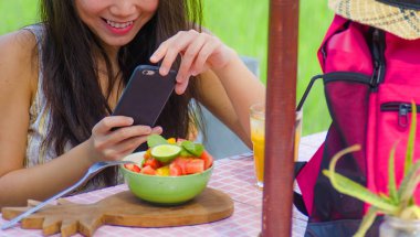 cep telefonu ekran alarak resmi internet sosyal medya uygulaması üzerinde sağlıklı beslenme yaşam tarzı ve gıda İnceleme blogger kavramı paylaşımı için meyve salatası ve portakal suyu olan kadın kırpılmış yüz