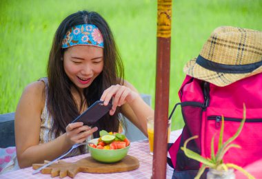 mutlu genç ve oldukça dijital göçebe Asyalı Koreli kadın meyve salatası cep telefonu ağ ile Internet sosyal medyada sağlıklı beslenme ve seyahat blogger Gıda çekim gözden geçirin