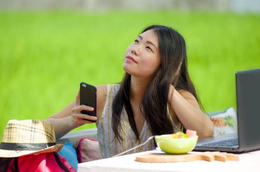 Genç güzel ve mutlu Asya dijital göçebe veya açık havada dizüstü bilgisayar ve cep telefonu Internet serbest iş iş ve yaşam tarzı ile ağ Çinli turist kadın