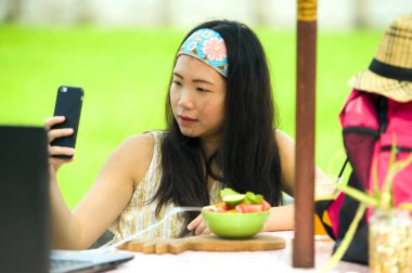 Genç güzel ve mutlu Asya dijital göçebe veya açık havada dizüstü bilgisayar ve cep telefonu Internet serbest iş iş ve yaşam tarzı ile ağ Çinli turist kadın 