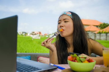 Genç güzel ve mutlu Asya dijital göçebe ya da Çinli turist kız açık havada sağlıklı salata Internet serbest iş iş ve yaşam tarzı kavramı içinde zevk dizüstü bilgisayar ile ağ