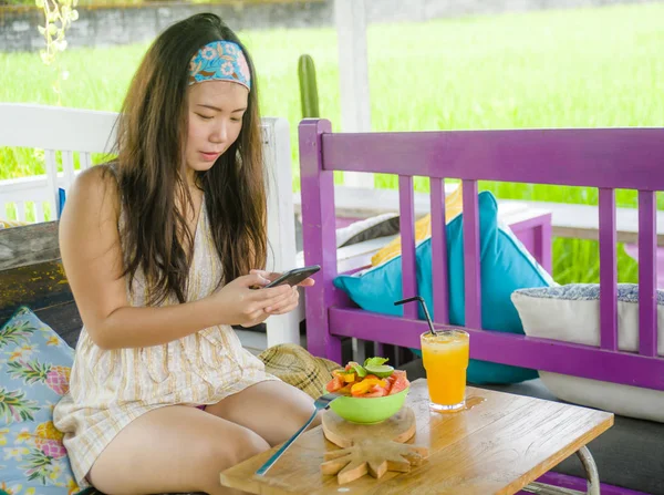 mutlu genç ve oldukça dijital göçebe Asya Çinli kadın alarak resmi meyve salatası ile sağlıklı beslenme ve seyahat blogger gıda inceleme internet sosyal medyada paylaşım için hareket eden telefon