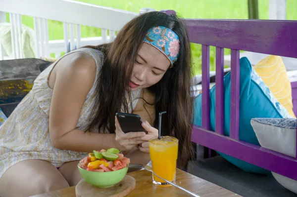 mutlu genç ve oldukça dijital göçebe Asya Çinli kadın meyve salatası cep telefonu ağ ile Internet sosyal medyada sağlıklı beslenme ve seyahat blogger Gıda çekim gözden geçirin