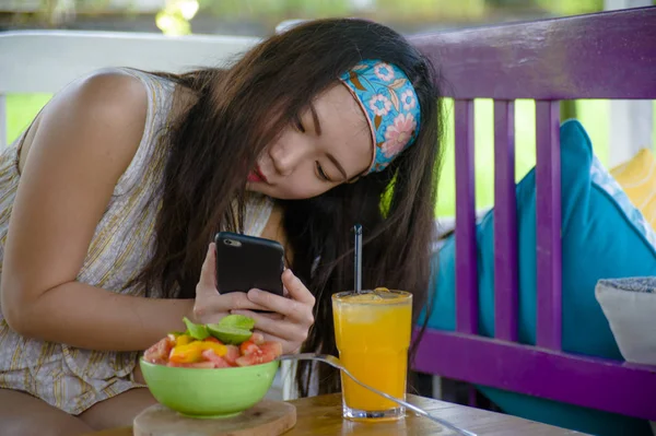 Genç mutlu ve meyve salatası cep telefonu ağ ile resmi internet sosyal medyada sağlıklı beslenme ve seyahat blogger gıda alarak oldukça dijital göçebe Asya Koreli kız gözden geçirin