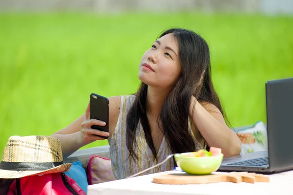 Genç güzel ve mutlu Asya dijital göçebe veya açık havada dizüstü bilgisayar ve cep telefonu Internet serbest iş iş ve yaşam tarzı ile ağ Çinli turist kadın