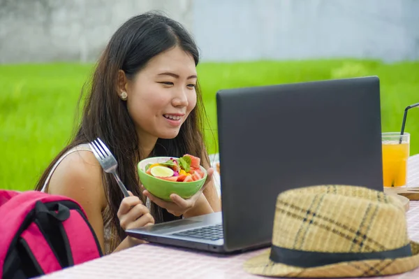 Genç güzel ve mutlu Asya dijital göçebe ya da Çinli turist kız açık havada sağlıklı salata Internet serbest iş iş ve yaşam tarzı kavramı içinde zevk dizüstü bilgisayar ile ağ