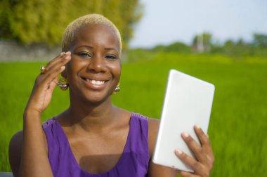 Tablet pad açık havada yeşil alan arka plan dijital göçebe başarı ve online sosyal medya eğlence neşeli gülümseyen tarih kullanan genç çekici ve mutlu başarılı siyah afro Amerikan kadın