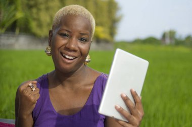 Tablet pad açık havada yeşil alan arka plan dijital göçebe başarı ve online sosyal medya eğlence neşeli gülümseyen tarih kullanan genç çekici ve mutlu başarılı siyah afro Amerikan kadın