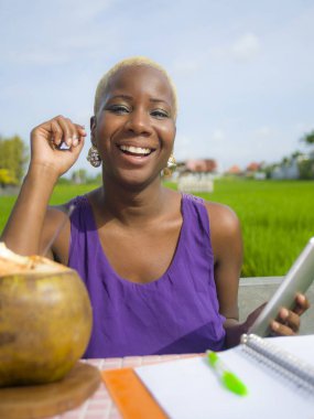Dijital tablet pad ile açık havada yeşil alan café dijital göçebe başarı ve online serbest iş neşeli gülümseyen üzerinde çalışan genç çekici ve mutlu başarılı siyah afro Amerikalı kadın