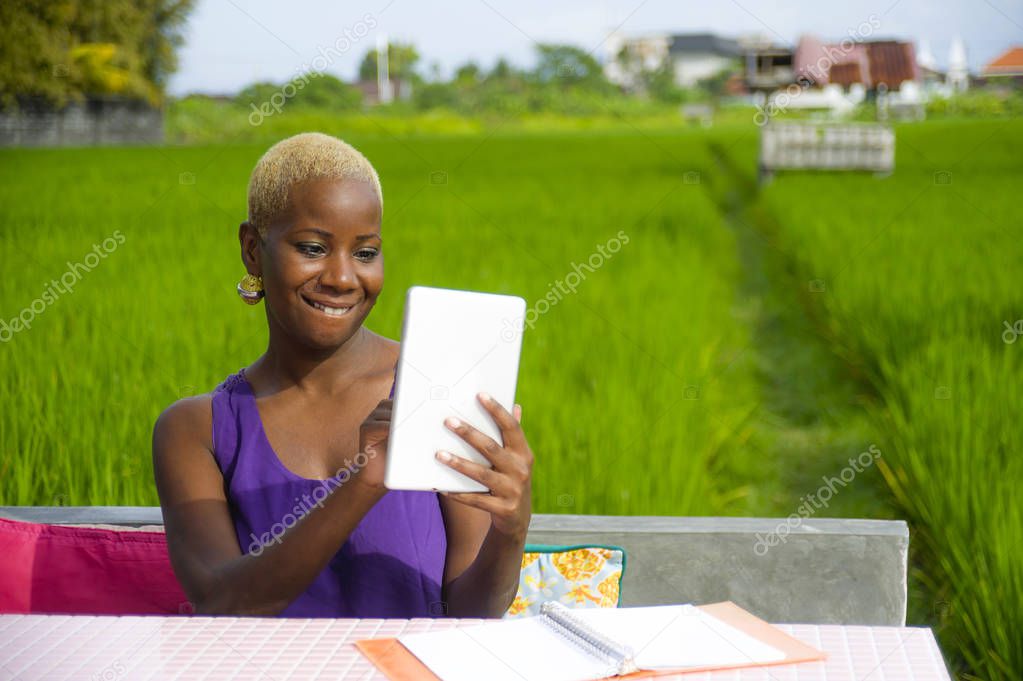 young attractive and happy successful black afro american woman working with digital tablet pad outdoors on green field cafe smiling cheerful in digital nomad success and online freelance job