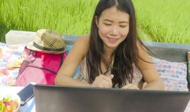 Açık havada yeşil çim arka plan dijital göçebe ve Internet serbest iş kavramı kafede ağ dizüstü bilgisayar ile çalışan genç güzel ve mutlu Asyalı Koreli kadın