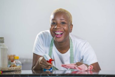 neşeli ve olumlu yerli ev işleri ve temizlik bezi gülümseyen ev mutfak temizlik kauçuk çamaşır içinde genç güzel ve mutlu Afrika kökenli Amerikalı siyah kadın