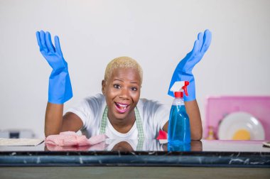 neşeli ve olumlu yerli ev işleri ve temizlik bezi gülümseyen ev mutfak temizlik kauçuk çamaşır içinde genç güzel ve mutlu afro Amerikalı siyah kadın