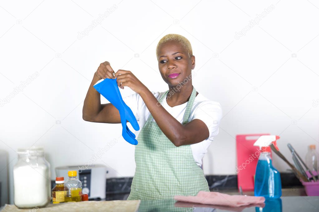 young attractive and happy black african american woman cleaning home  kitchen putting  blue washing rubber gloves smiling cheerful in domestic housekeeping and housework concept
