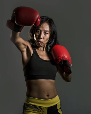 Genç uygun Asyalı kadın fitness üst ve boks eldiven atma kızgın ve savaşta meydan okuyan kötü kız tutumunda punch ve savaşmak terbiye izole koyu arka plan üzerinde Çince portresi kapatın