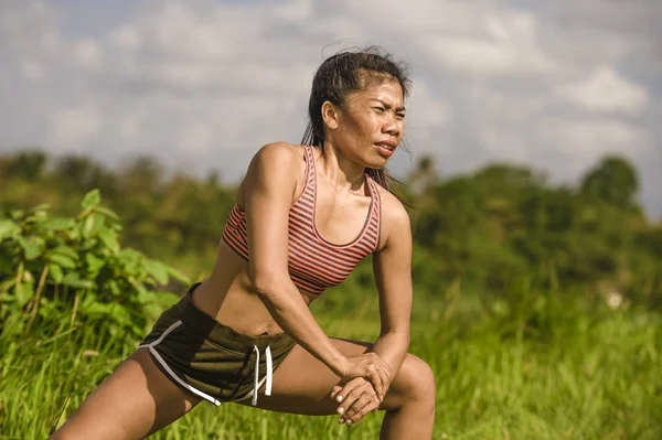 zinde ve sportif orta yaşlı runner Asyalı kadın germe bacak ve vücut egzersiz yeşil çalıştırdıktan sonra spor eğitim ve sağlıklı yaşam konsepti güzel arka plan alanı