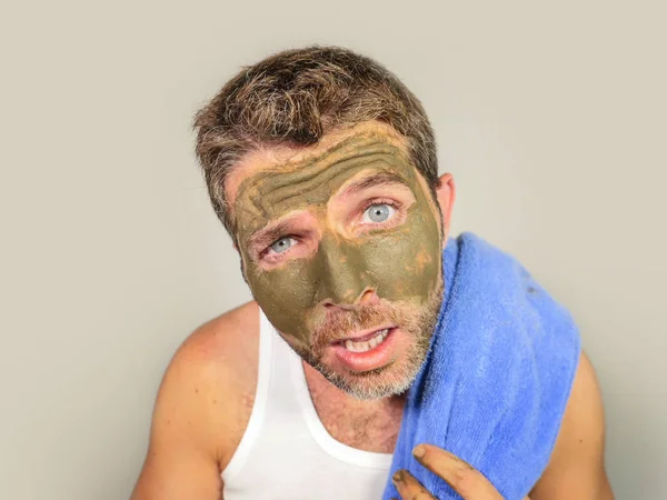 若い厄介な面白い男が見て彼自身嫌な男性化粧品コンセプトの醜い感じ美容マスク製品を適用する彼の顔に緑のクリームとバスルームの鏡でゾッとしました — ストック写真